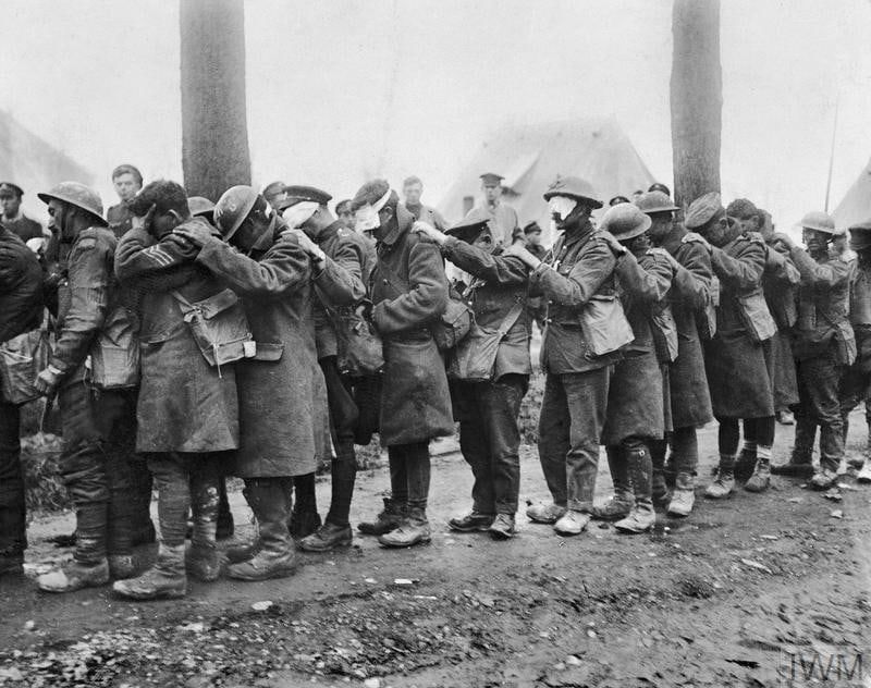 British soldiers of the 55th West Lancashire Division, blinded by tear gas during the German Spring Offensive of 1918, line up for treatment at an Advanced Dressing Station near Bethune, France, By the end of WW1, 124,000 tons of poison gas had been produced by all sides.